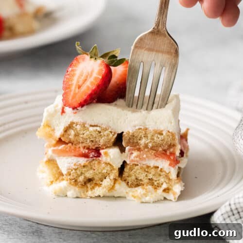 Slice of strawberry tiramisu on a plate with a fork.