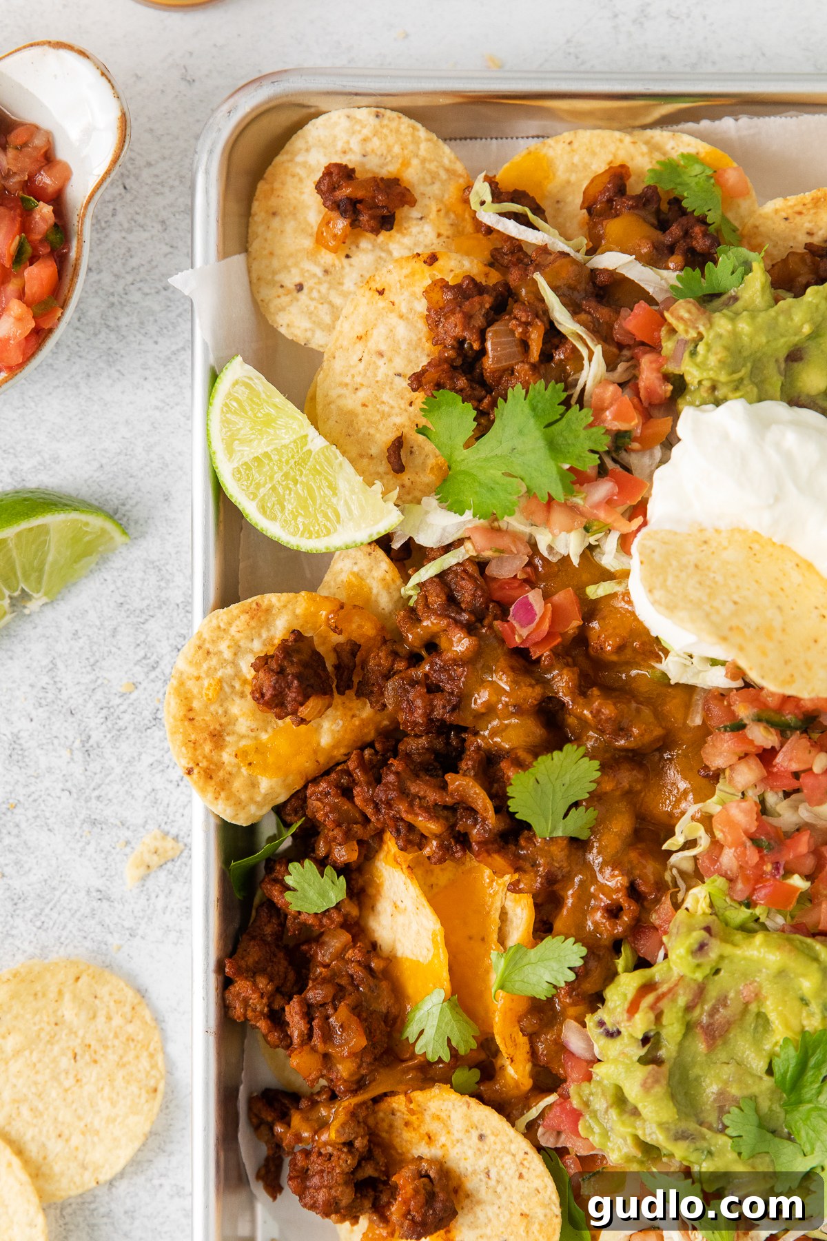 Beef nachos on a baking sheet, freshly baked with melted cheese and ready for toppings.