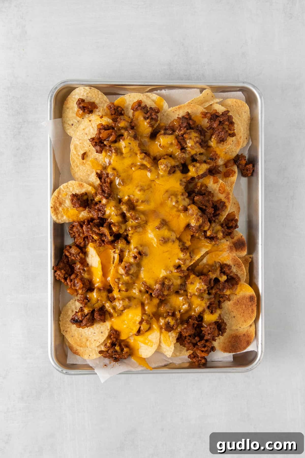 Nachos topped with ground beef and melted cheese, fresh from the oven, before adding cold toppings.