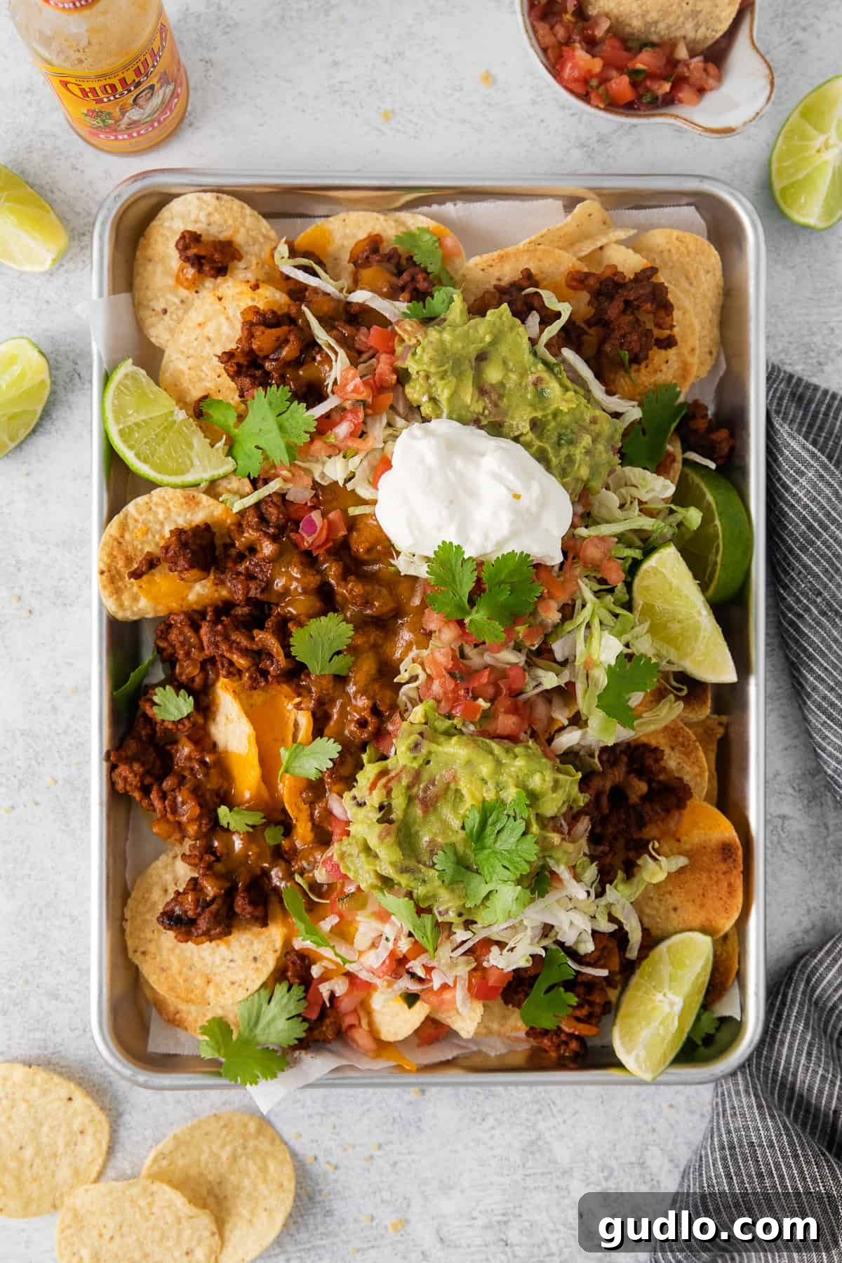 Ground beef nachos topped with all the fixings, including guacamole, sour cream, and fresh vegetables.