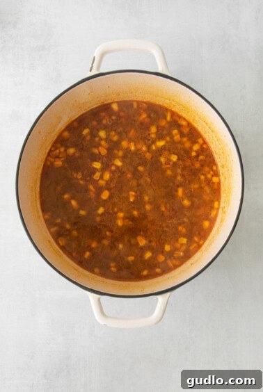 A pot of soup with corn and other vegetables simmering, enriching the flavors.