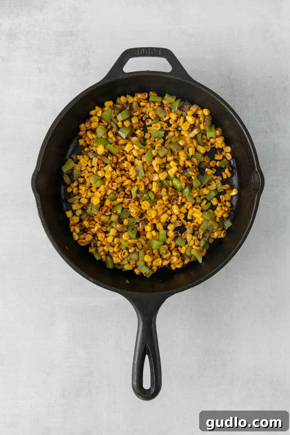 Perfectly charred corn kernels in a cast iron skillet, a key component for authentic Elote flavor in the soup.