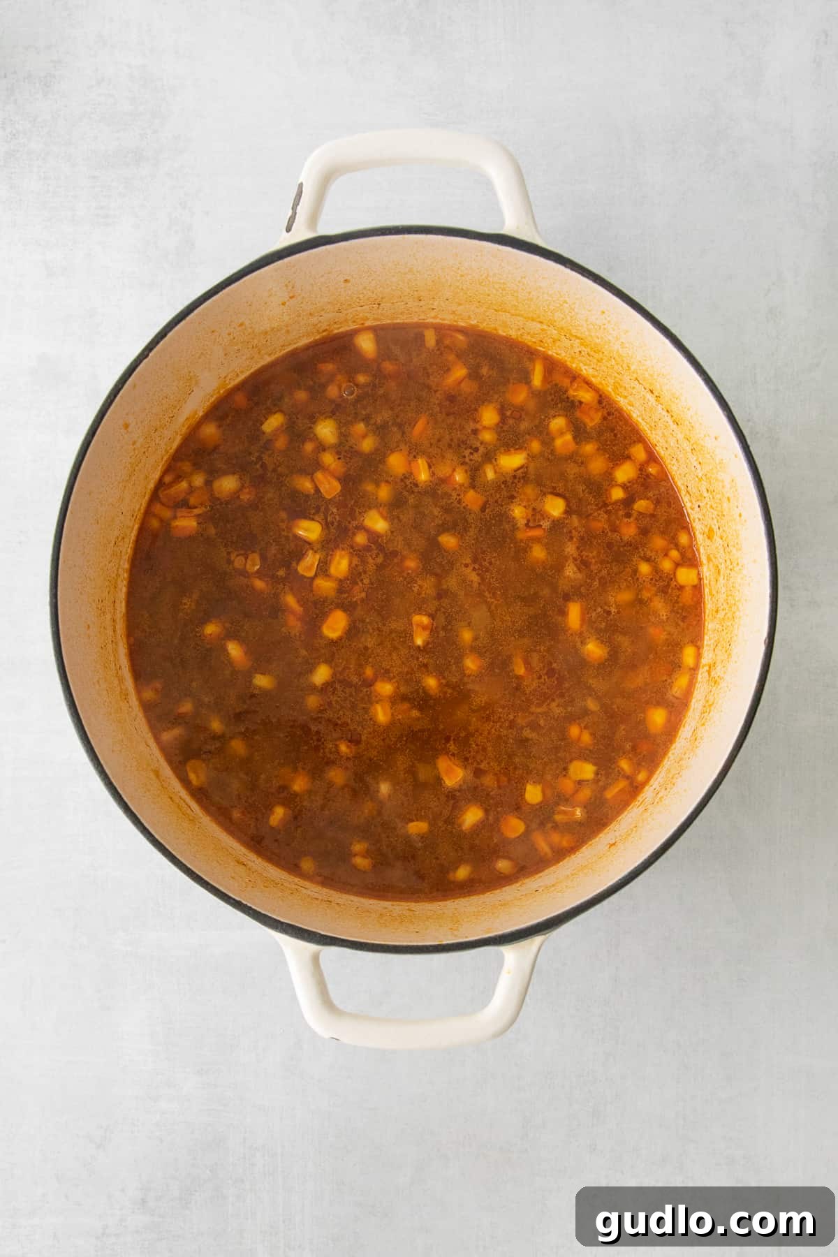 Mexican Street Corn Soup simmering gently in a large stockpot, showcasing its rich, creamy texture and colorful ingredients before blending.