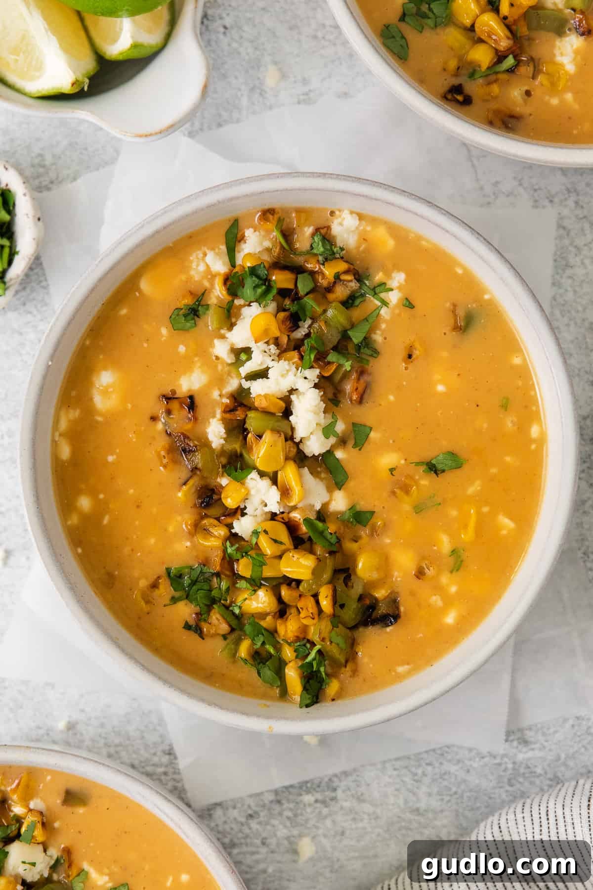A close-up shot of Mexican Street Corn Soup in a rustic bowl, garnished with fresh cilantro and a lime wedge, highlighting its inviting texture.