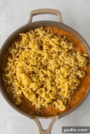 Creamy macaroni and cheese mixed with taco meat in a skillet.