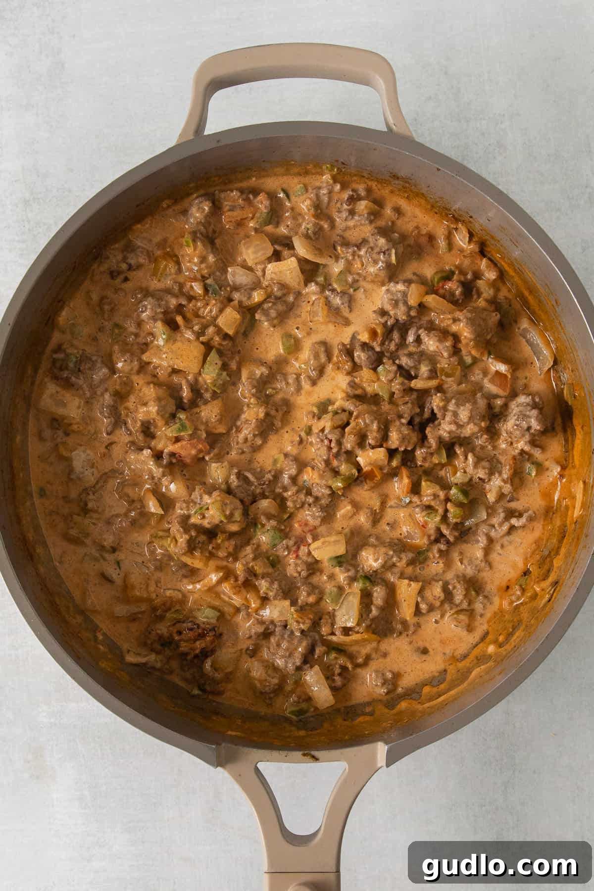 Building the Creamy Base for Taco Mac and Cheese Ground beef and heavy cream simmering together in a skillet, creating a rich base for the mac and cheese.
