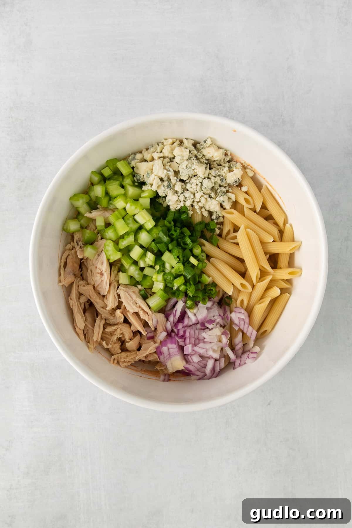 A white bowl filled with the creamy buffalo dressing ingredients mixed and whisked until smooth, showcasing its rich texture and color.