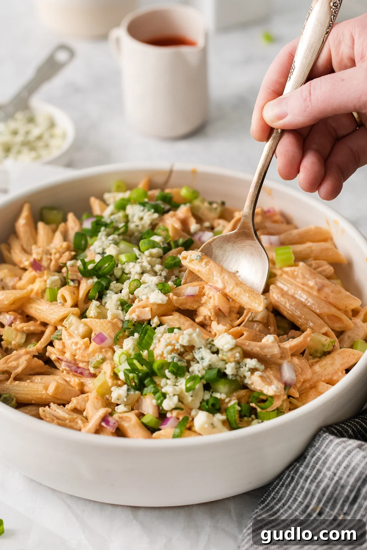 A close-up shot of buffalo chicken pasta salad being scooped onto a spoon, highlighting the creamy sauce, tender chicken pieces, and crisp celery bits.