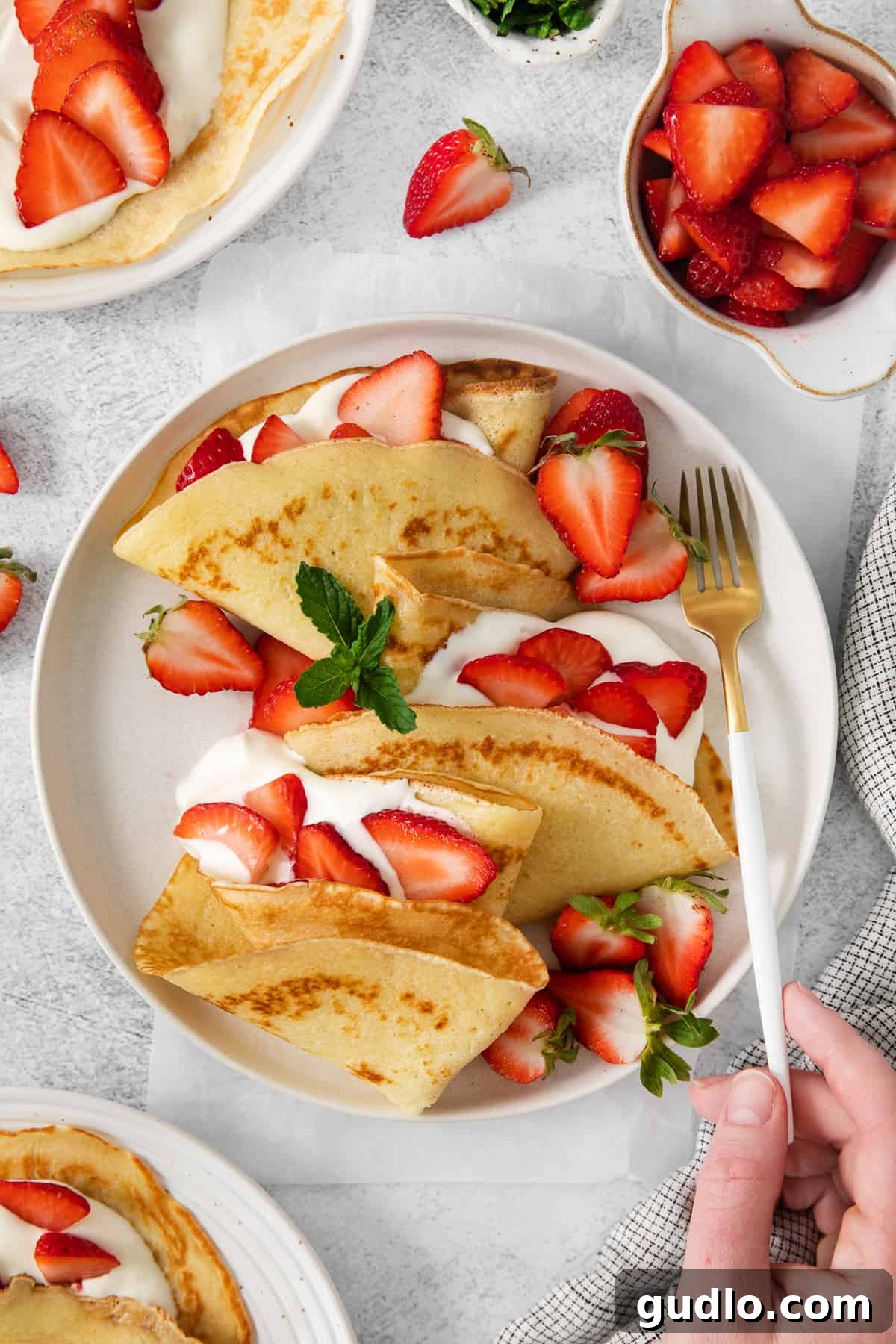 Beautifully plated strawberry crepes, golden brown with a sweet cream cheese and fresh strawberry filling.
