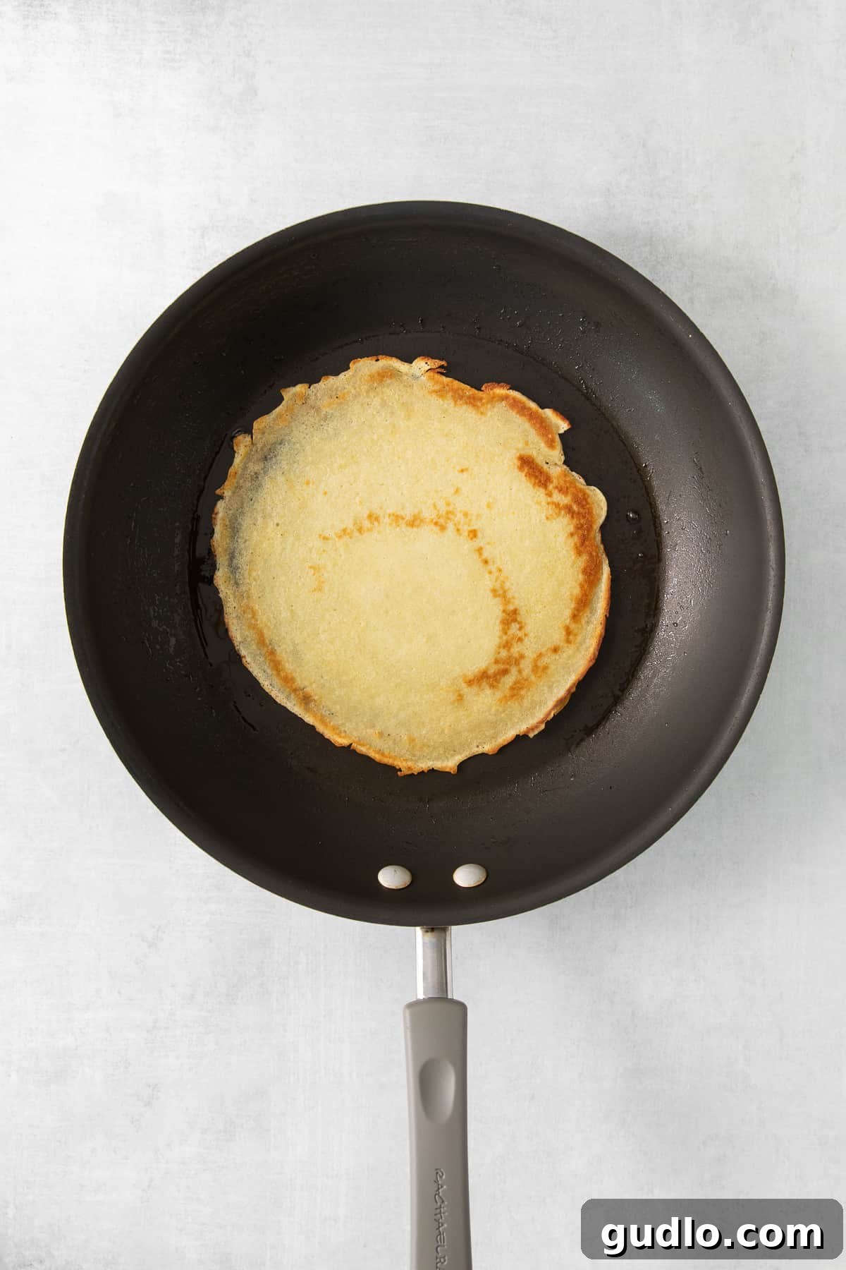 A delicate crepe cooking to golden perfection in a nonstick skillet.