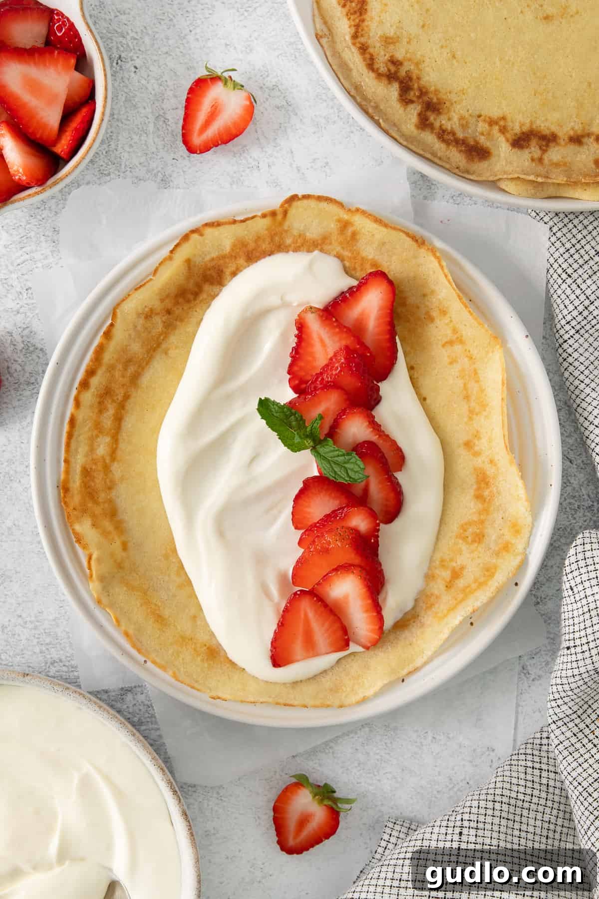 A perfectly folded strawberry crepe, garnished with fresh mint, ready to be enjoyed.