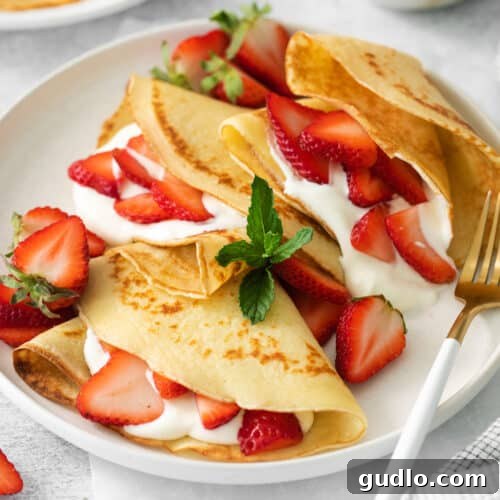 Strawberry cream cheese crepes on a plate, captured from a top-down angle.