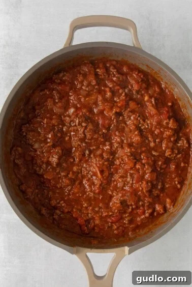 Ground beef simmering in a rich marinara sauce in a large skillet.