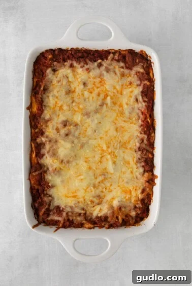 A casserole dish filled with baked Million Dollar Spaghetti, showing the golden-brown mozzarella top, resting after baking.