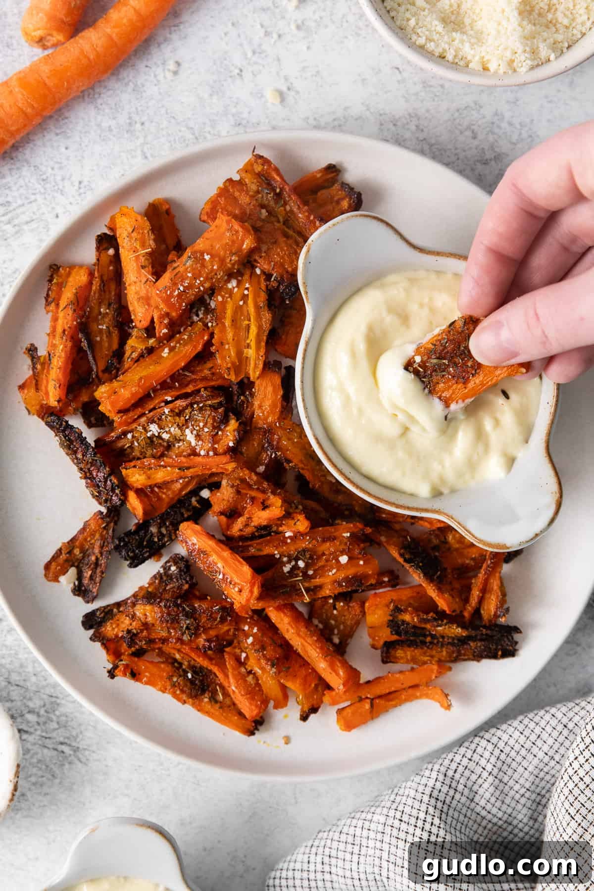 Delicious Parmesan Smashed Carrots with Aioli Crispy Parmesan smashed carrot dipped into a creamy homemade aioli sauce, showcasing its golden-brown exterior and tender interior.