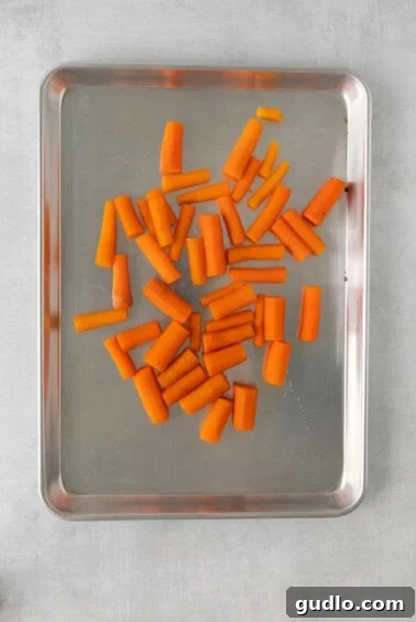 Uniformly sliced carrots spread on a baking sheet after boiling.