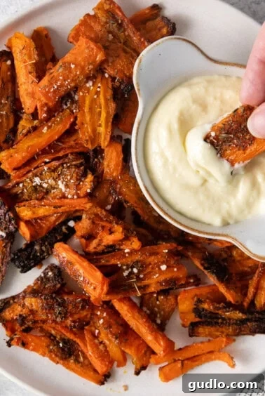 A plated serving of Parmesan smashed carrots with a side of creamy aioli.