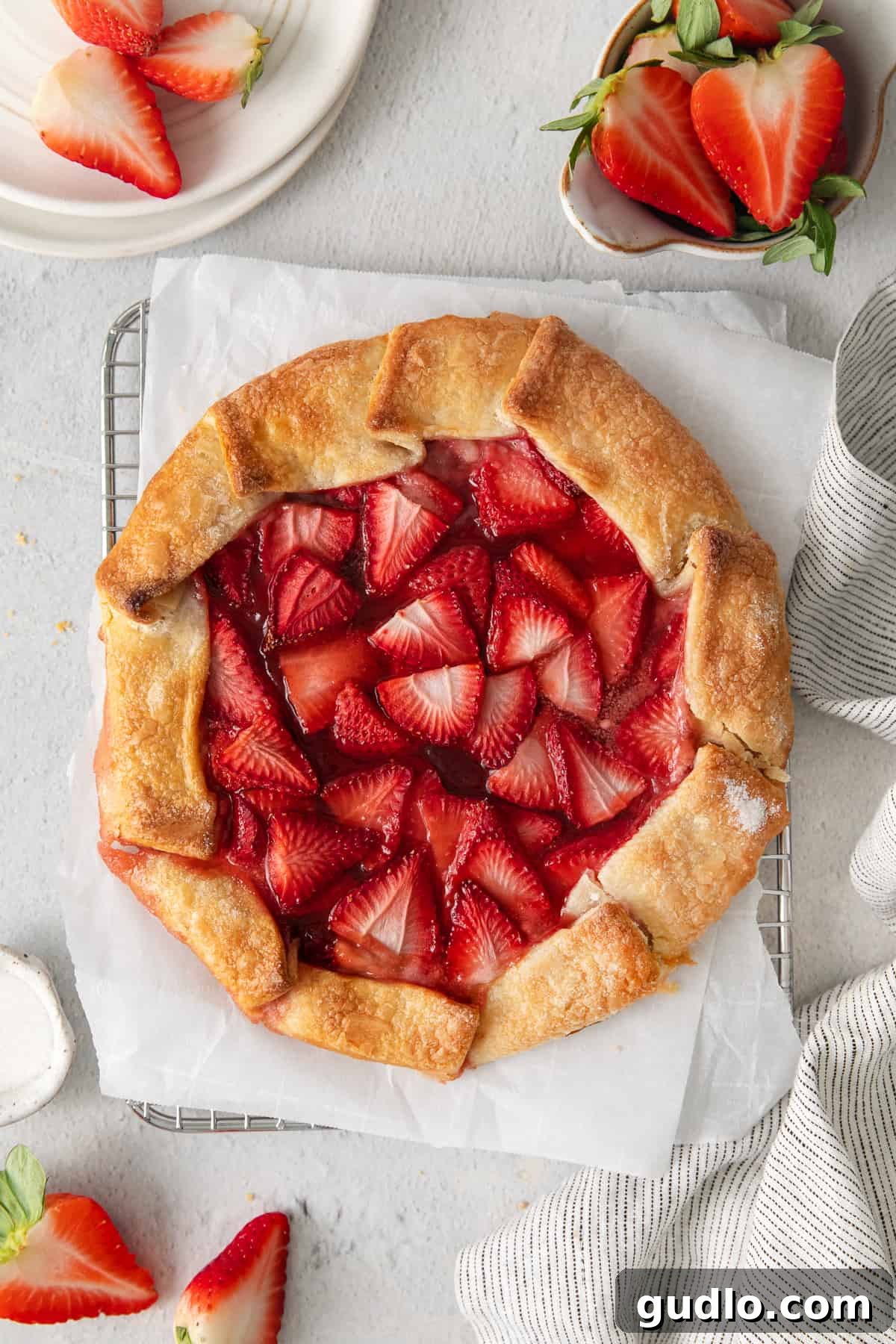 A perfectly baked strawberry cream cheese tart featuring a golden, slightly crimped crust and glossy, sweet strawberries, cooling gracefully on a wire rack.