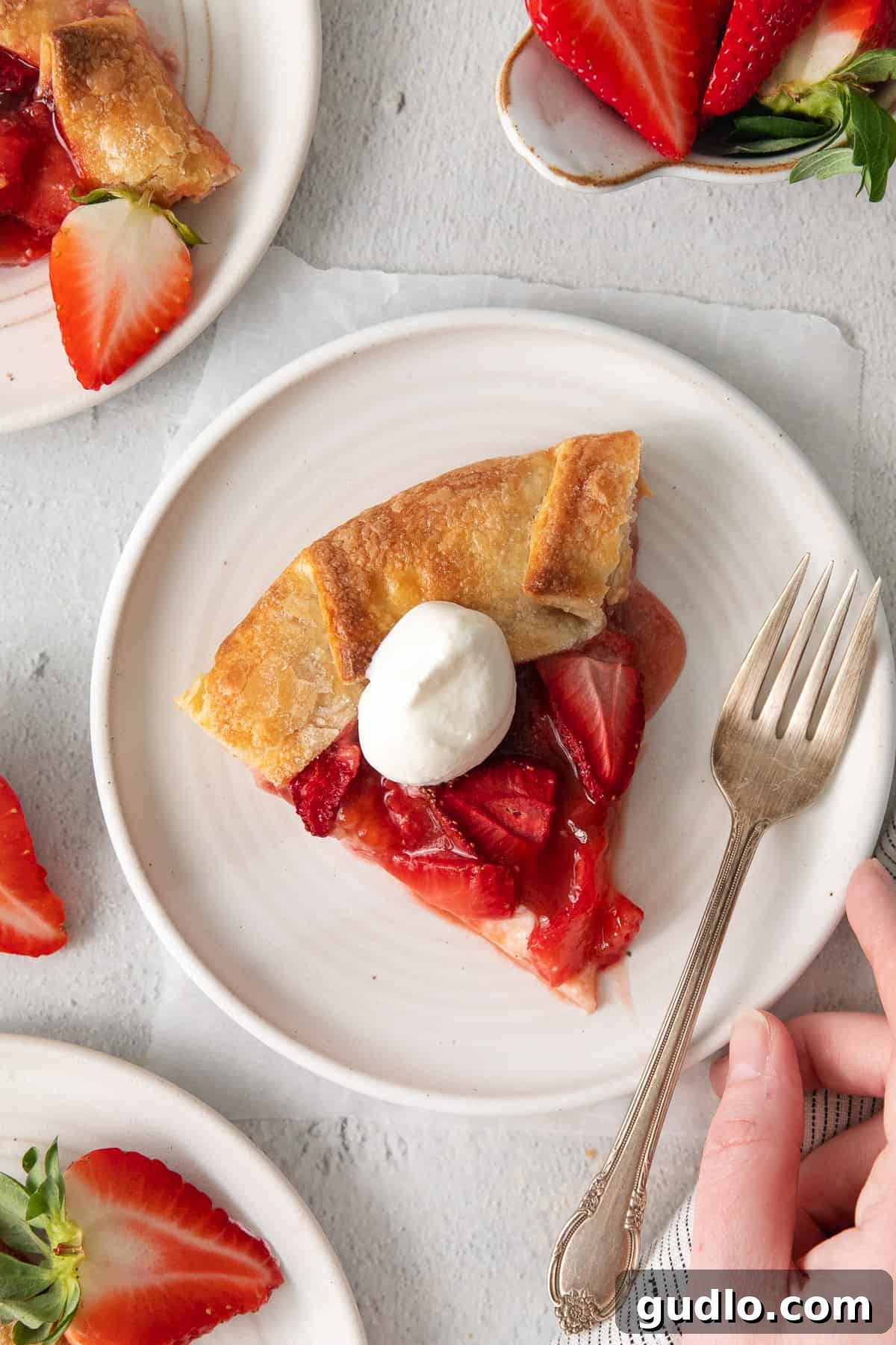 A delectable slice of strawberry cream cheese tart elegantly presented on a pristine white plate, showcasing its distinct layers of flaky crust, luscious cream cheese filling, and fresh, vibrant strawberries.