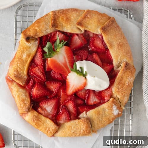 A beautifully baked strawberry cream cheese tart, golden and glistening with fresh strawberries, topped with a dollop of whipped cream, ready for serving.