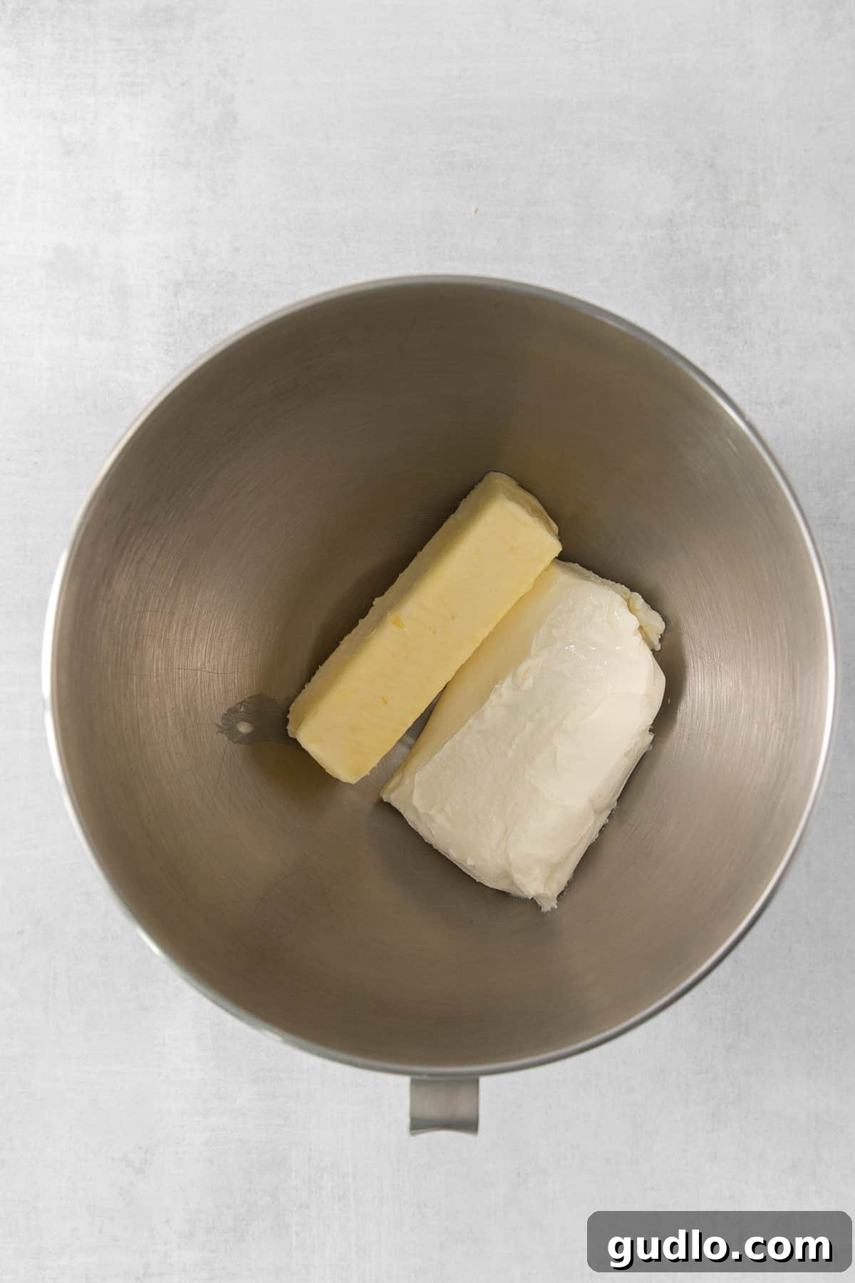 Key Ingredients for Cream Cheese Frosting Softened cream cheese and unsalted butter mingling in a metal mixing bowl, ready to be whipped.