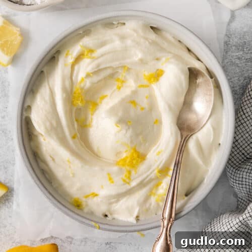 Lemon cream cheese frosting in a bowl, garnished with zest.