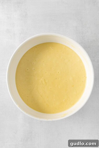Luminous Lemon Olive Oil Cake 13 A bowl of lemon olive oil cake batter, a smooth and pale yellow mixture, ready for baking.