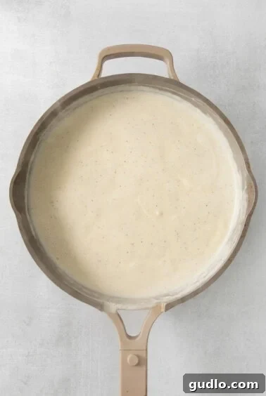 Alfredo sauce with cheese melting in a pan.