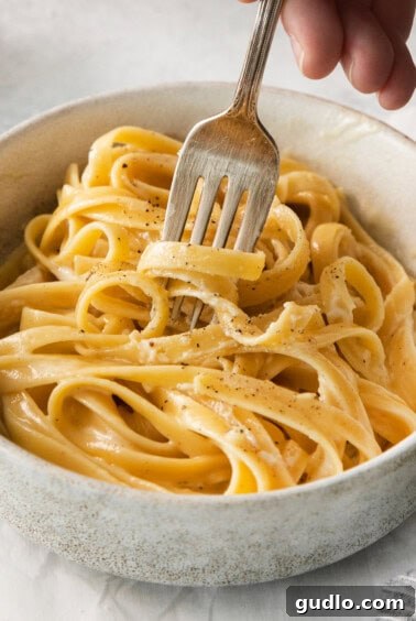 Homemade alfredo sauce over pasta in a bowl.
