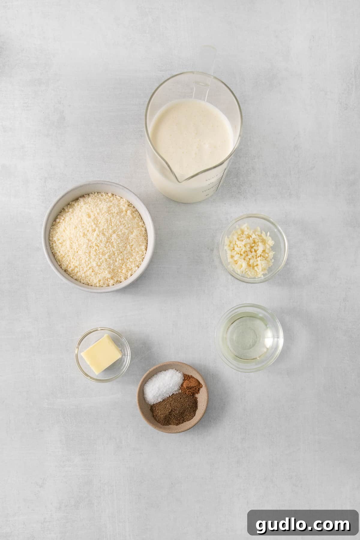 Fresh Ingredients for Homemade Alfredo Sauce A selection of fresh ingredients for Alfredo sauce, including butter, garlic, Parmesan, and cream, neatly arranged in bowls.