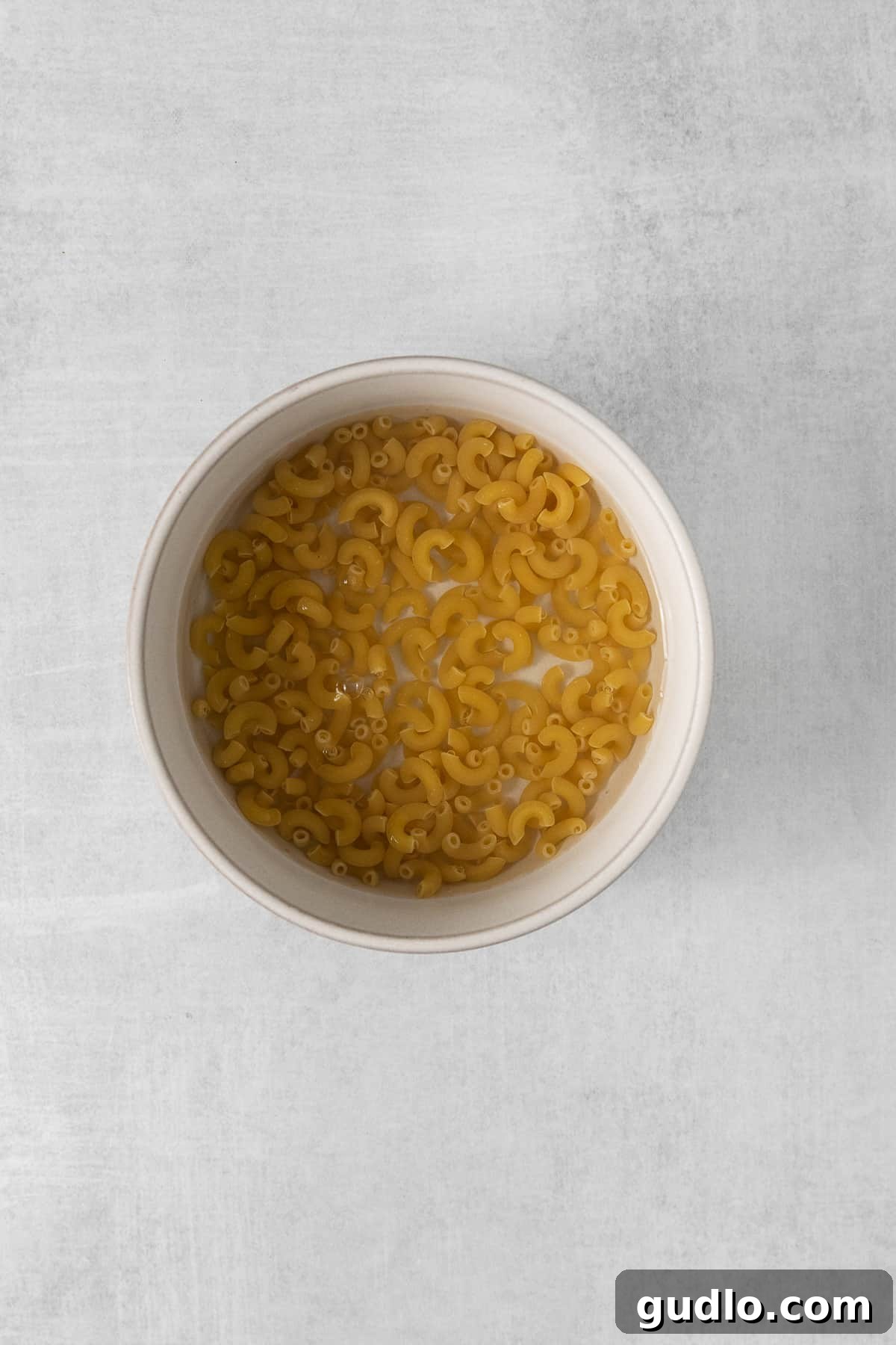 Microwave Mac and Cheese: Cooking the Noodles Macaroni noodles in a bowl of water, ready for the microwave.