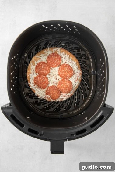 Air Fryer Frozen Pizza Perfection 3 A frozen pizza being carefully placed into a preheated air fryer basket.