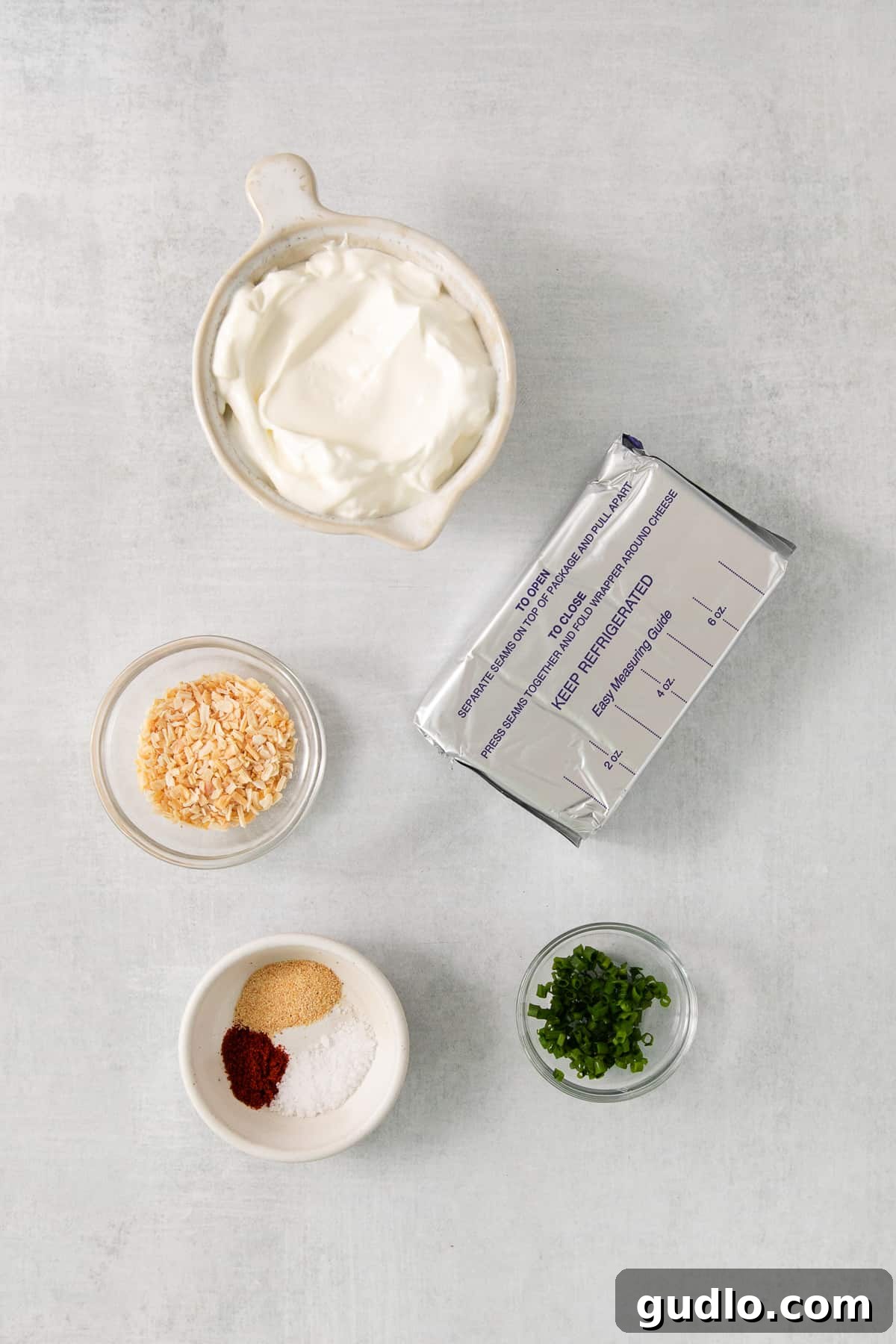Key Ingredients for Homemade Chip Dip Bowls of cream cheese, sour cream, dried onion, garlic powder, salt, paprika, and fresh chives, ready to be combined for the chip dip.
