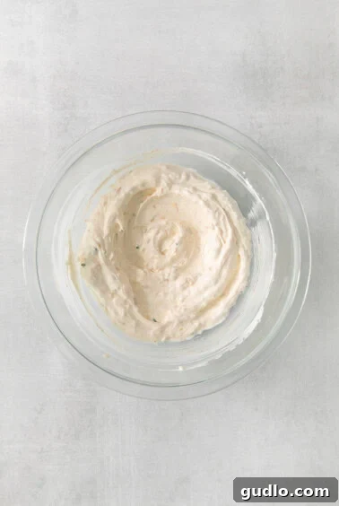 The Ultimate Classic Chip Dip 3 A bowl of creamy dip being mixed with a hand mixer.