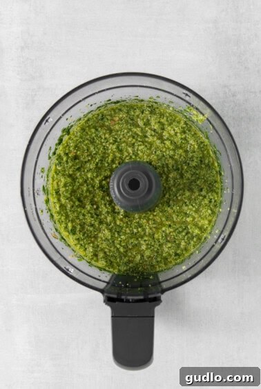 a food processor filled with green pesto.