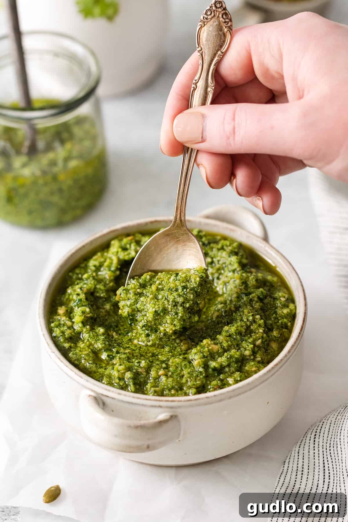 Cilantro pesto in a bowl with a spoon, highlighting its texture and color.