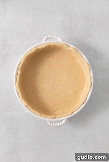 A pre-baked pie crust in a white pie dish, ready for filling.