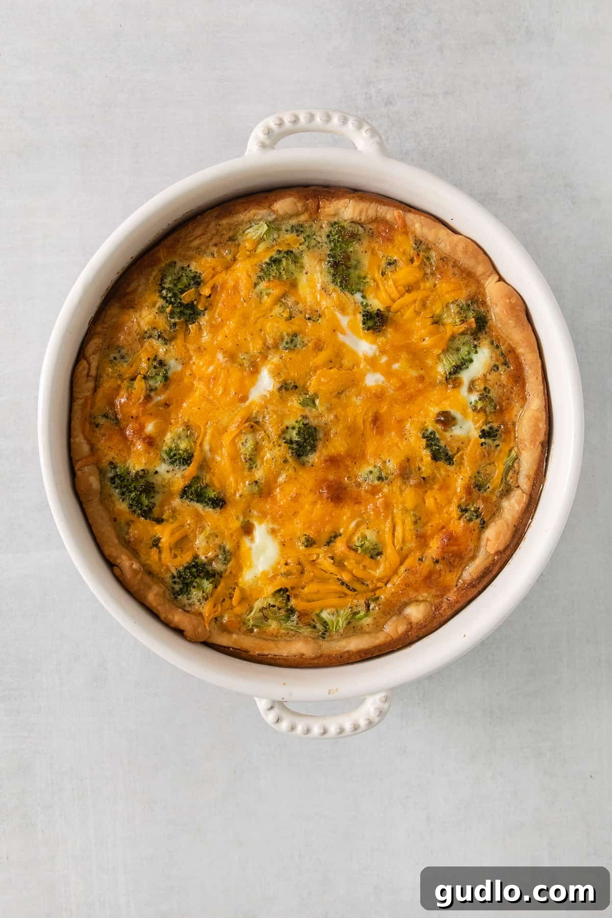 A fully baked broccoli and cheese quiche, still in its pie dish, ready for serving.