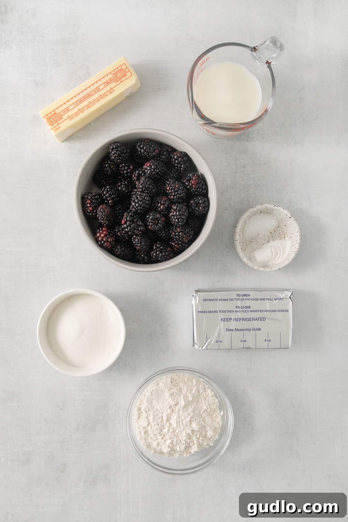 Tangy Blackberry Cream Cheese Cobbler 3 A collection of fresh ingredients laid out for baking, including blackberries, milk, butter, and flour.