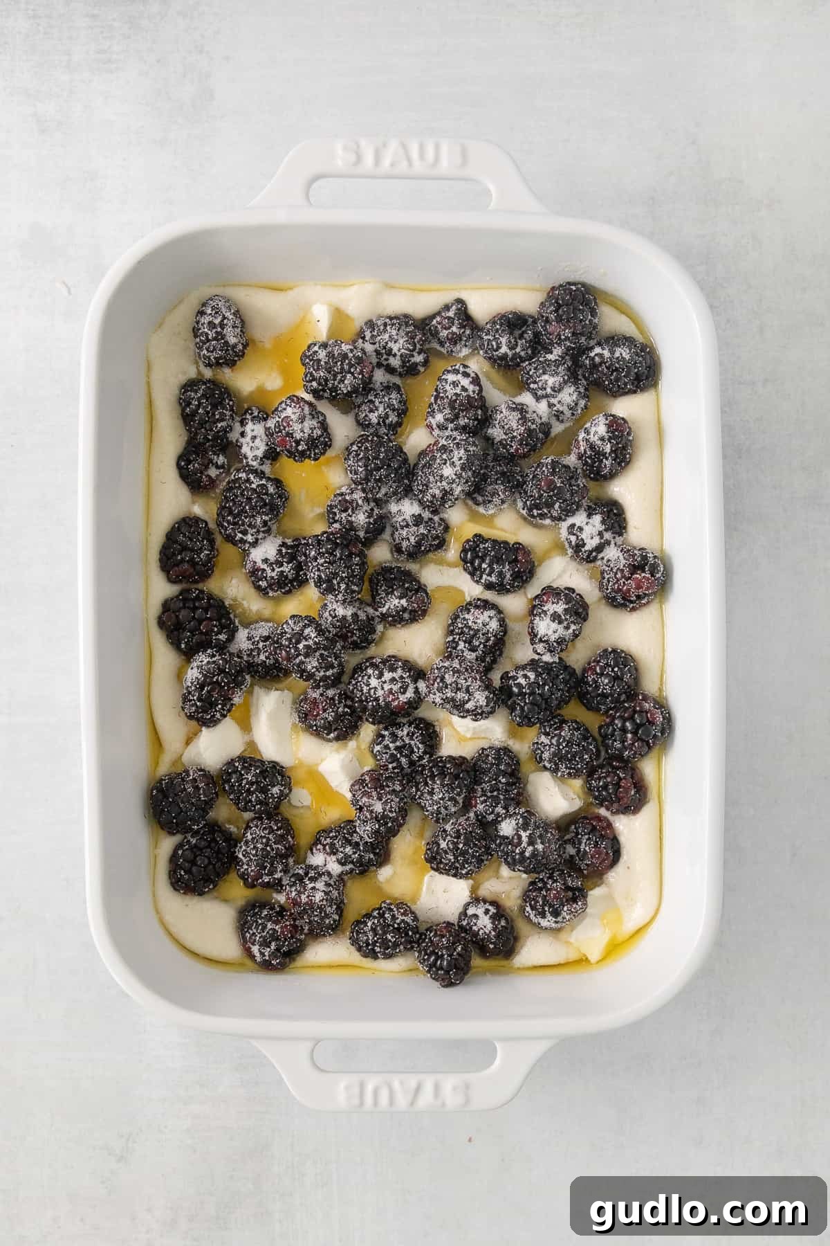 Tangy Blackberry Cream Cheese Cobbler 5 A freshly baked cream cheese blackberry cobbler, bubbling with fruit, resting in a white casserole dish.
