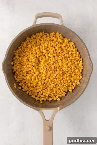 Ultimate Cream Cheese Corn Dip 10 A frying pan filled with corn cooking on the stove.