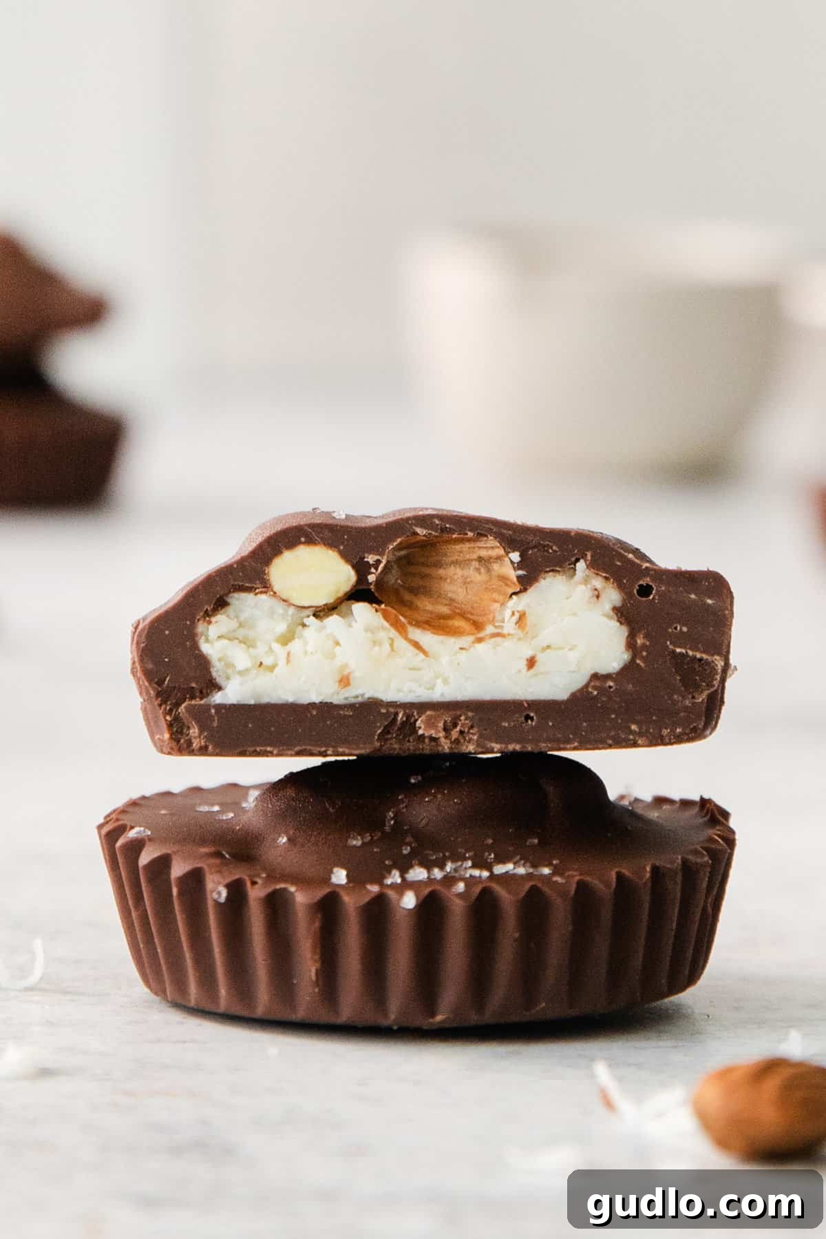 DIY Almond Joys 2 Two pieces of homemade Almond Joy candy bars stacked on top of each other, showcasing the chocolate and coconut layers.