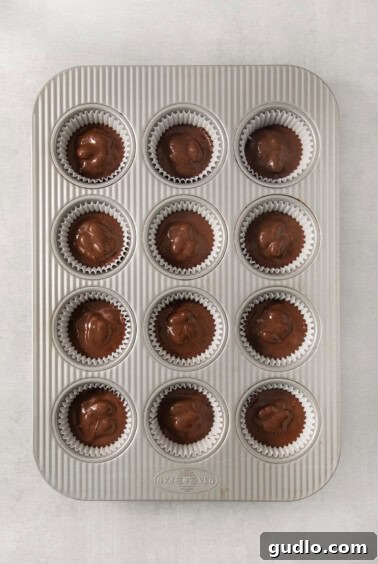 A muffin tin filled with chocolate-covered Almond Joy candies, fresh out of the freezer and ready to be served.
