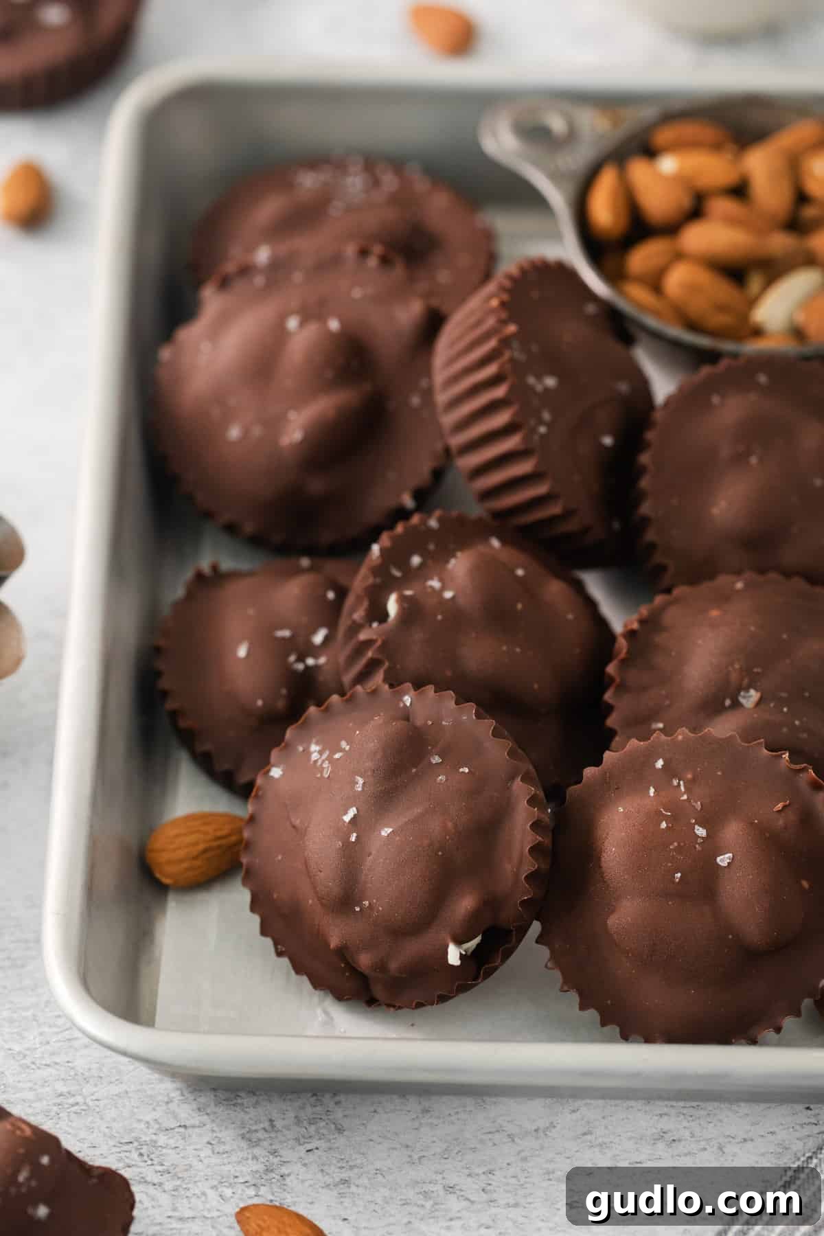 DIY Almond Joys 3 A rustic wooden tray filled with an assortment of homemade chocolate and coconut candies, some topped with nuts.