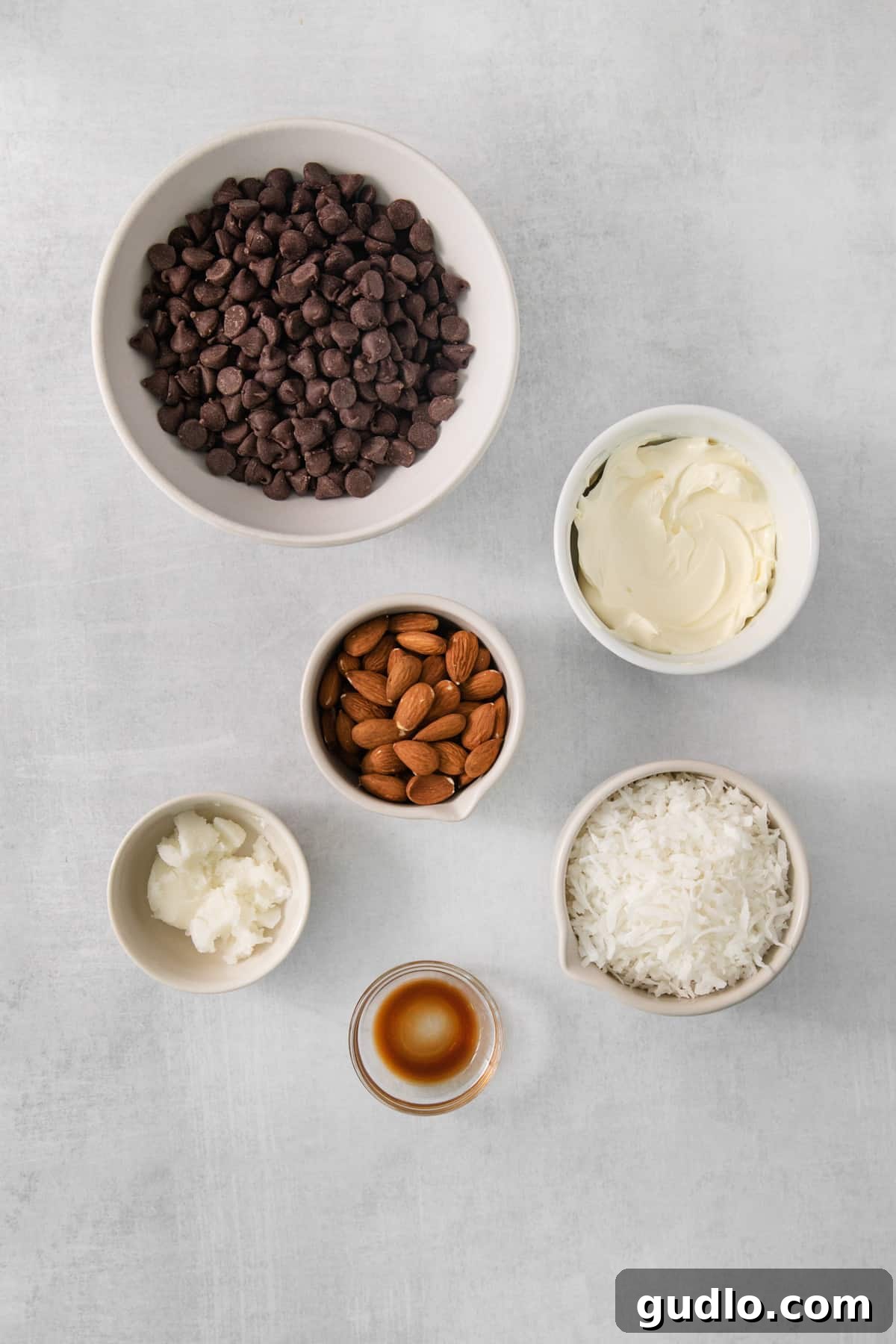 DIY Almond Joys 5 A beautifully arranged table featuring bowls filled with various ingredients for candy making, including chocolate chips, shredded coconut, and whole almonds.