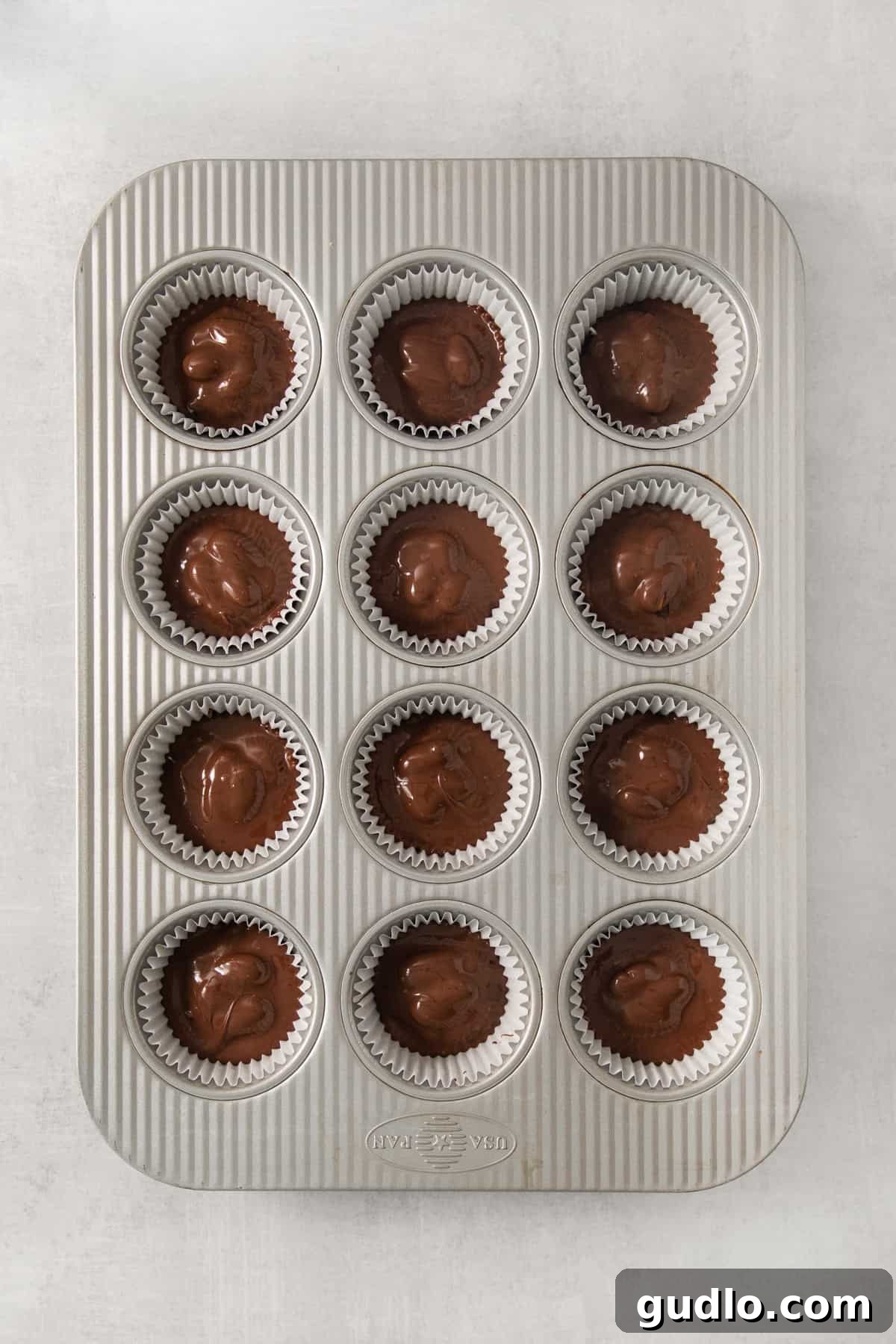 DIY Almond Joys 7 A muffin tin filled with freshly made chocolate and coconut candies, glistening with a smooth chocolate coating, ready to be enjoyed.