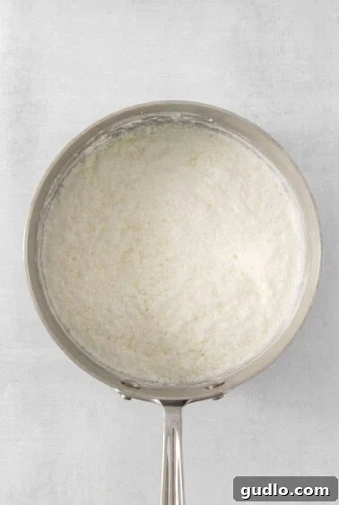 A pan with white curds separating from translucent liquid, illustrating the curdling process.