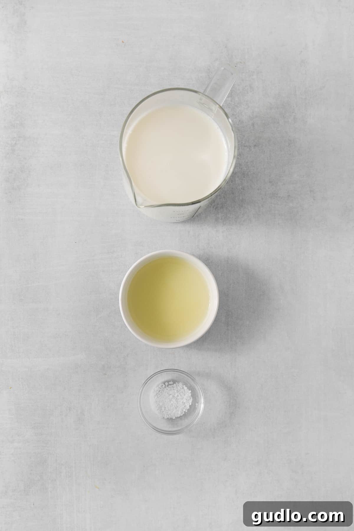 A rustic setup featuring a bowl of fresh milk and a bowl of sugar, against a soothing gray backdrop, symbolizing the purity of ingredients.