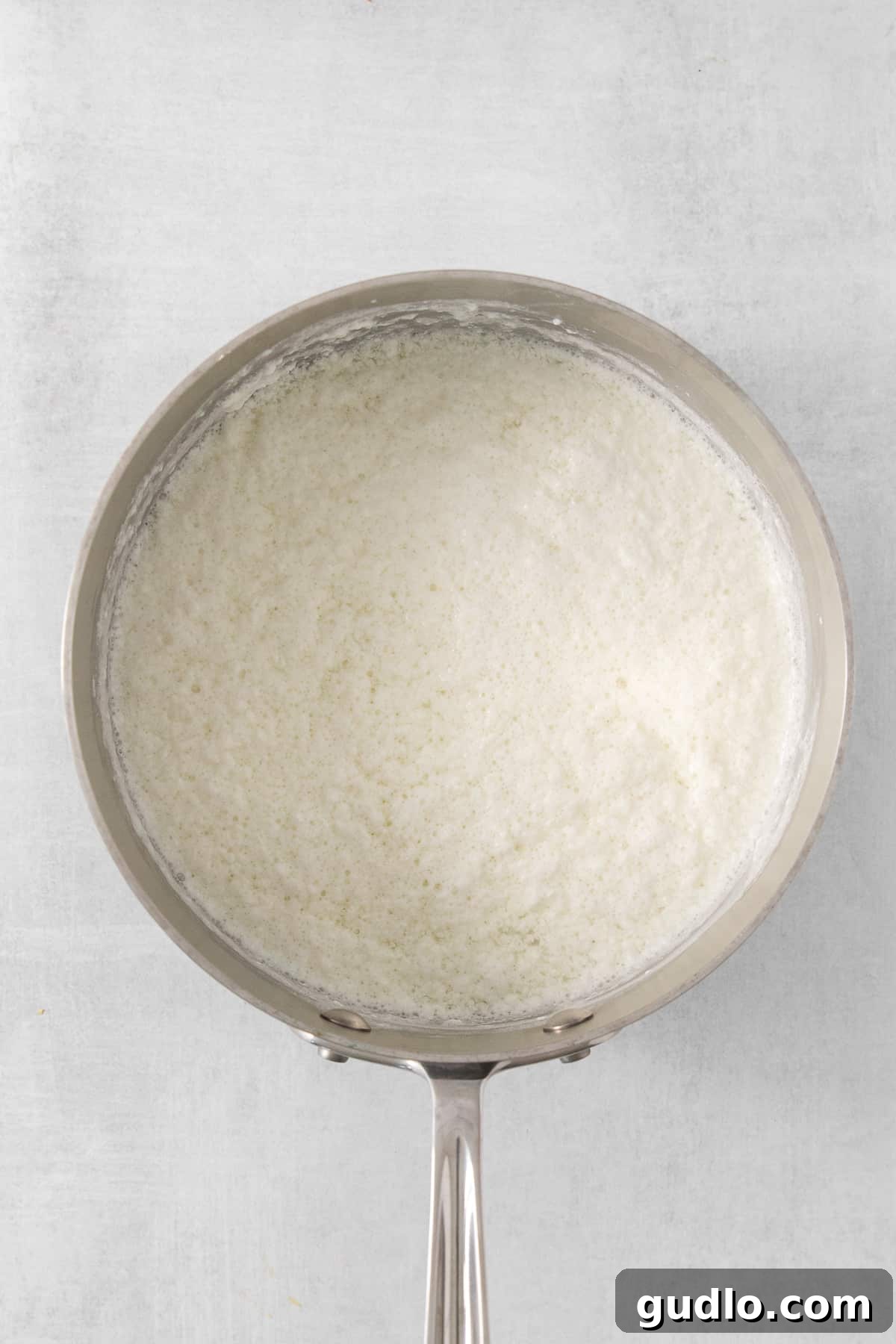 Close-up of fluffy white rice in a pan on a clean white background, symbolizing purity and readiness for culinary transformation.