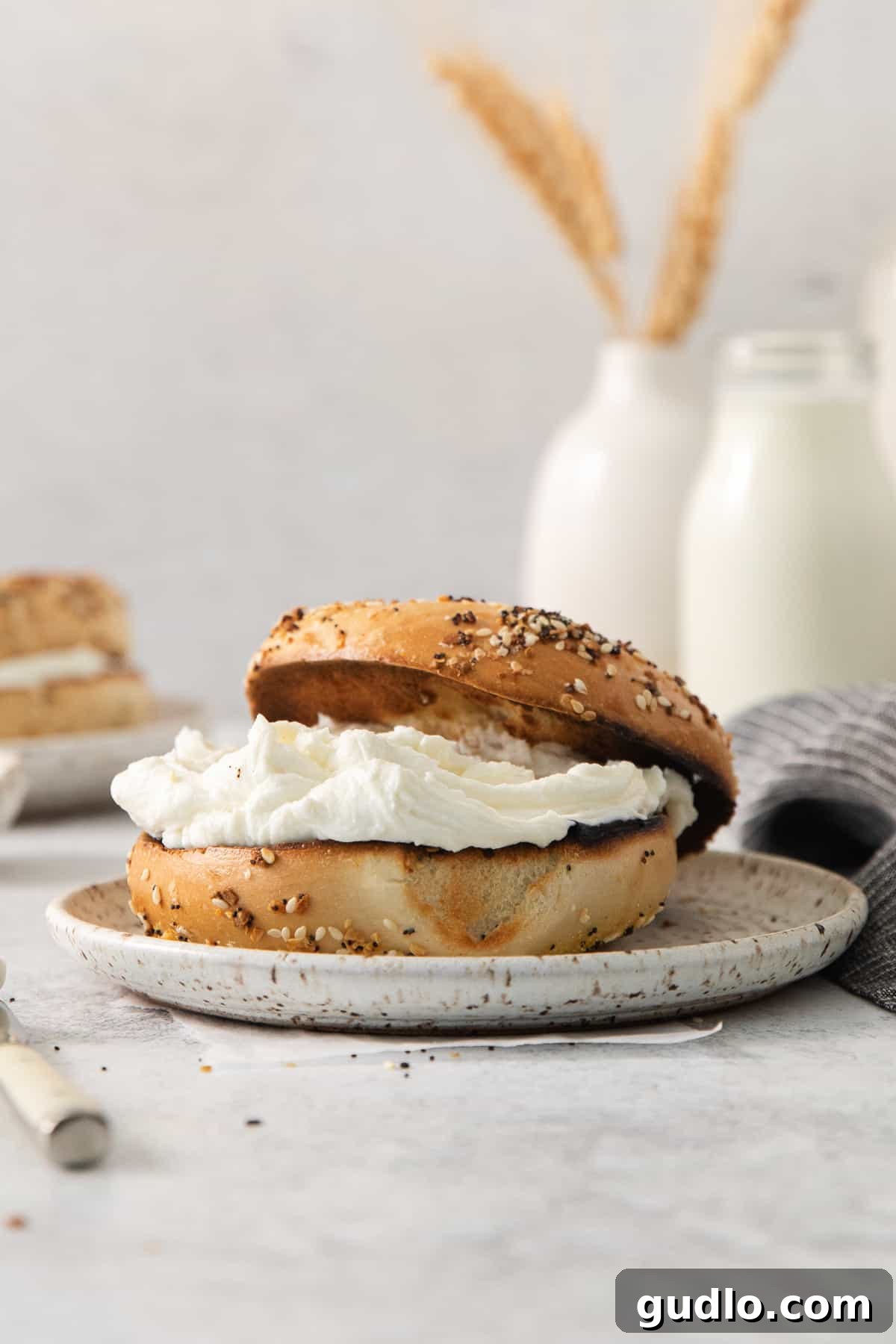 A perfectly toasted bagel with a generous smear of cream cheese, beautifully presented on a plate for a simple, satisfying meal.